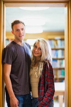 Portrait of a smiling young couple against blurred bookshelf in the library