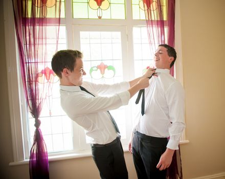Groom and his Best Man joking and playing while they dress up and get ready for the wedding