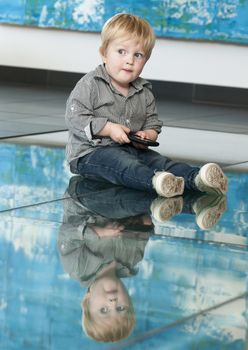 Cute little child playing with cellphone and reflexion on the floor