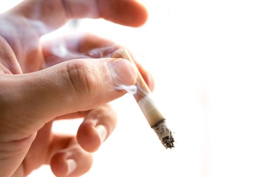 Male hand holding a cigarette on white background