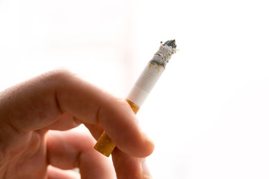 Male hand holding a cigarette on white background