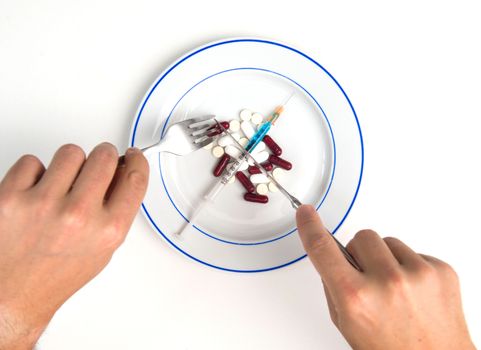 Medical Meal, Man hands with fork and Knife eating Tablets, Syringe and Pills on a plate