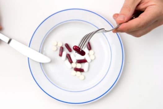 Medical Meal, Man hands with fork and Knife eating Tablets and Pills on a plate