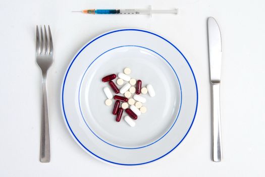 Medical Meal of pills and tablets on a plate with Fork, Knife and Syringe