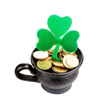 Black ceramic pot with golden coins and shamrock isolated on white. St. Patrick Day concept