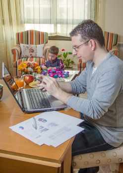 Father working hard in home office with smartphone and his boring son playing on the background