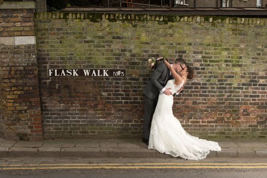 Happy couple kissing on their wedding day in front of their dream home in London