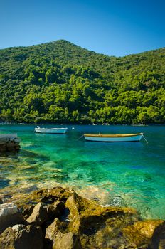 two boats in the water off the coastline of Mljet Croatia with the mountains in the back ground