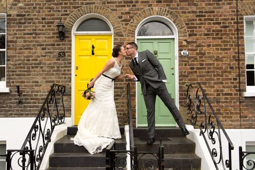 Happy couple kissing on their wedding day in front of their dream home in London