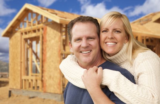 Happy Excited Couple in Front of Their New Home Construction Framing Site.