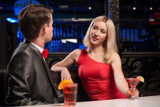 portrait of a woman in a nightclub, sitting on the couch and talking with man