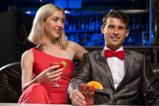 couple in a nightclub on the couch with a drink, have fun