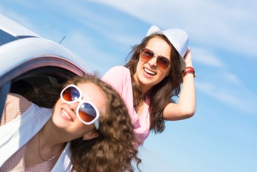 young attractive woman in sunglasses got out of the car window and laugh