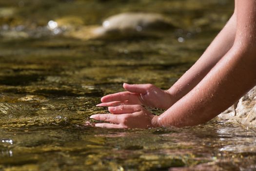 The hands in the cold clear water of the river