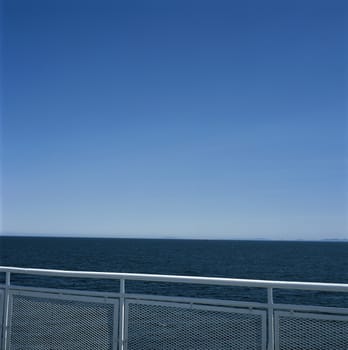White metal railing against the blue ocean