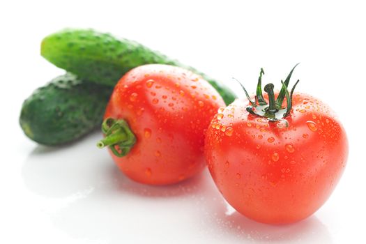 tomato with water drops and cucumbers isolated on white