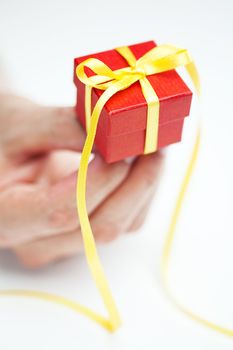 red gift box with a yellow ribbon in the hands of women