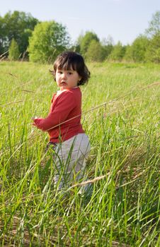 Little girl standing in high grass on sunny day