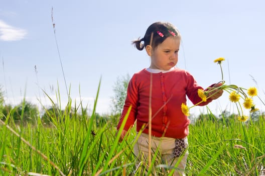 Little girl with flowers outdoor in nature