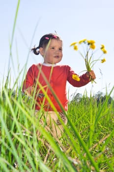 Small girl with flowers in high grass