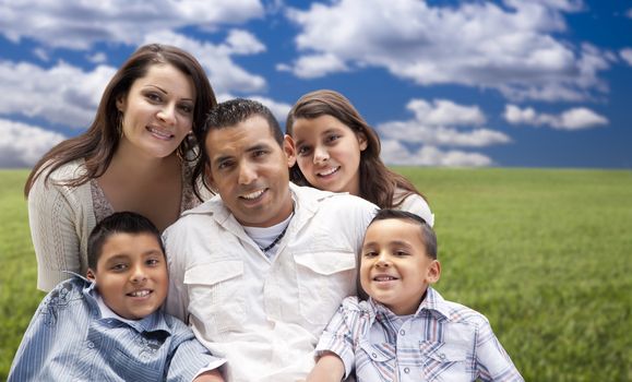 Happy Hispanic Family Portrait Sitting in Grass Field.
