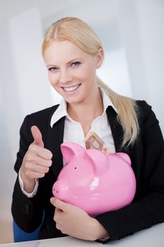 Businesswoman holding euro currency and piggybank in the office