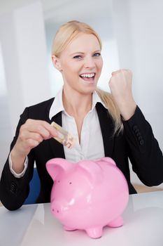Businesswoman holding euro currency and piggybank in the office