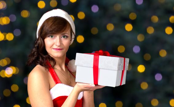 Christmas girl holding gift box with christmas lights on background
