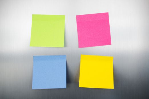 Close up of coloured reminders on fridge. Metallic background with reflections