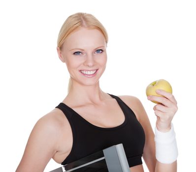 Beautiful young fitness woman with weights and apple. Isolated on white