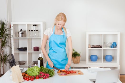 Cheerful young woman cooking in the kitchen