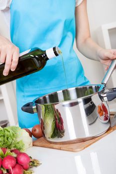 Cheerful young woman cooking in the kitchen