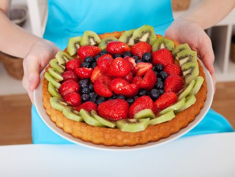 Close-up on woman holding self-made cake in the kitchen