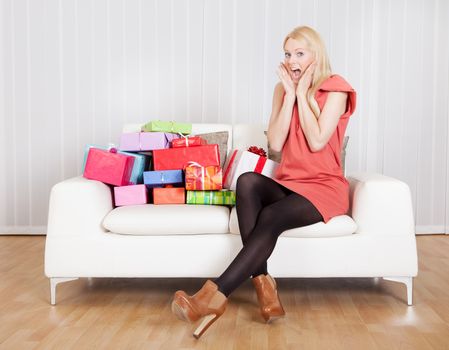 Beautiful young woman with her presents on the sofa
