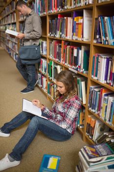 Concentrating student reading book on library floor at the university