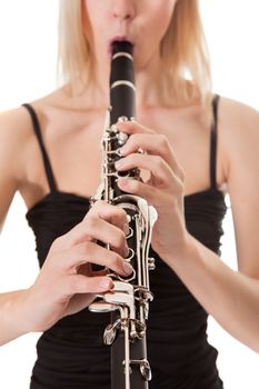 Beautiful young woman playing clarinet over black background