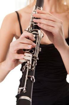 Beautiful young woman playing clarinet over black background