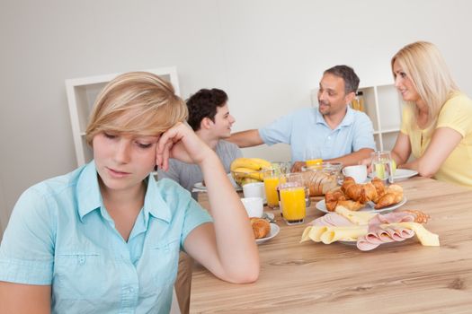 Sad young teenage girl sitting forlornly in the foreground