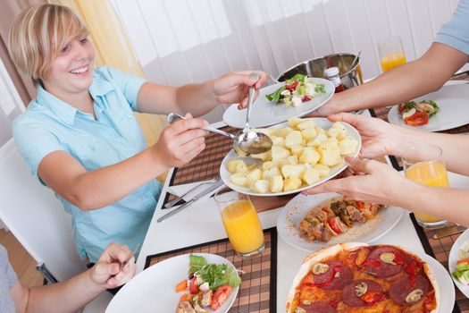 Young happy family with teenage children sitting down to eat a cold lunch of meat and salads