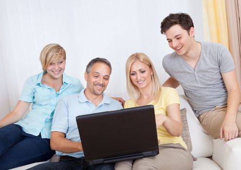 Smiling family together sitting on the couch with laptop