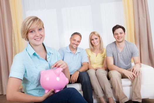 Attractive young teenage girl putting a coin in a pink piggy