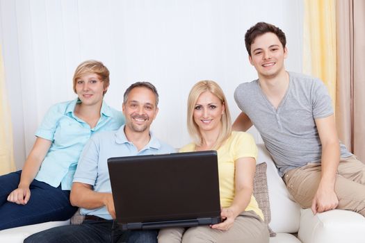 Smiling family together sitting on the couch with laptop