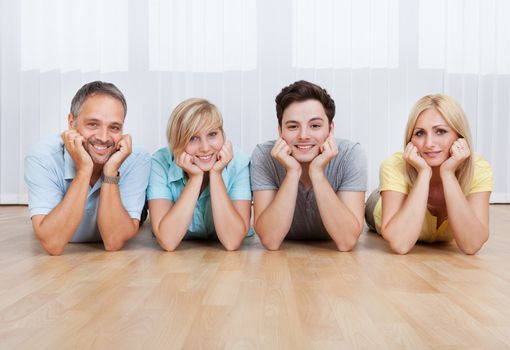 Joyful family lying on the floor with their heads close together