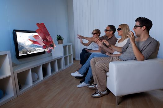 Conceptual image of a family watching 3D television and stretching out their hands as though to touch the image on the screen