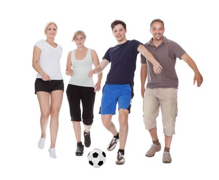 Active family with fit parents and two teenagers playing soccer running after a ball isolated on white