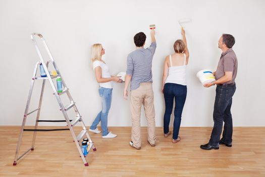 Family teamwork during home maintenance as the children repair the surface of the wall for their parents to paint