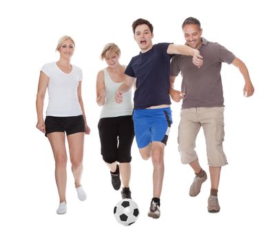 Active family with fit parents and two teenagers playing soccer running after a ball isolated on white