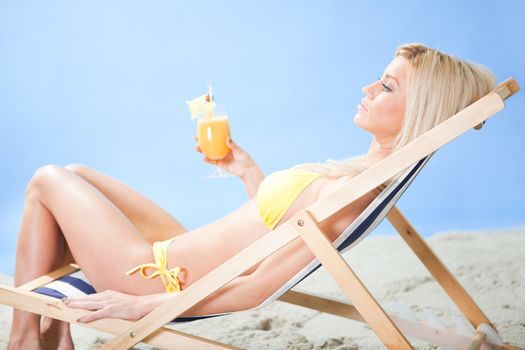 Beautiful young woman in bikini lying on a deckchair at the beach