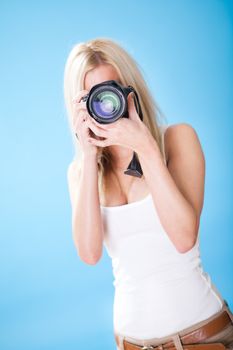 Portrait of beautiful young woman with camera on sky background