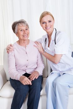 Portrait Of Young Doctor And Senior Patient Sitting On Couch